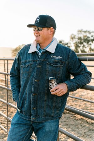Smiling man in denim jacket holding canned drink
